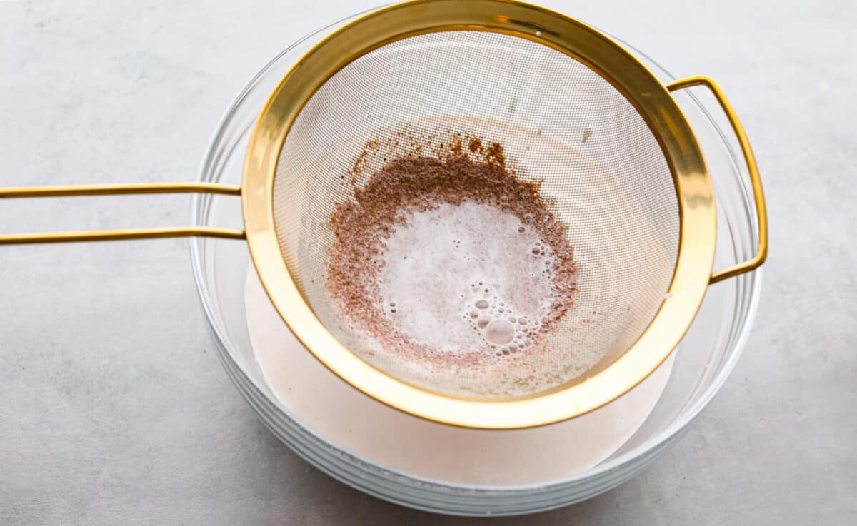 Elevate the flavors of traditional horchata with this strawberry horchata recipe! It's a creamy drink soaked in rice water and cinnamon sticks, then sweetened with a strawberry puree. Everyone loves the strawberry version of this rich, milky Mexican drink! Process photo of the rice water mixture straining.