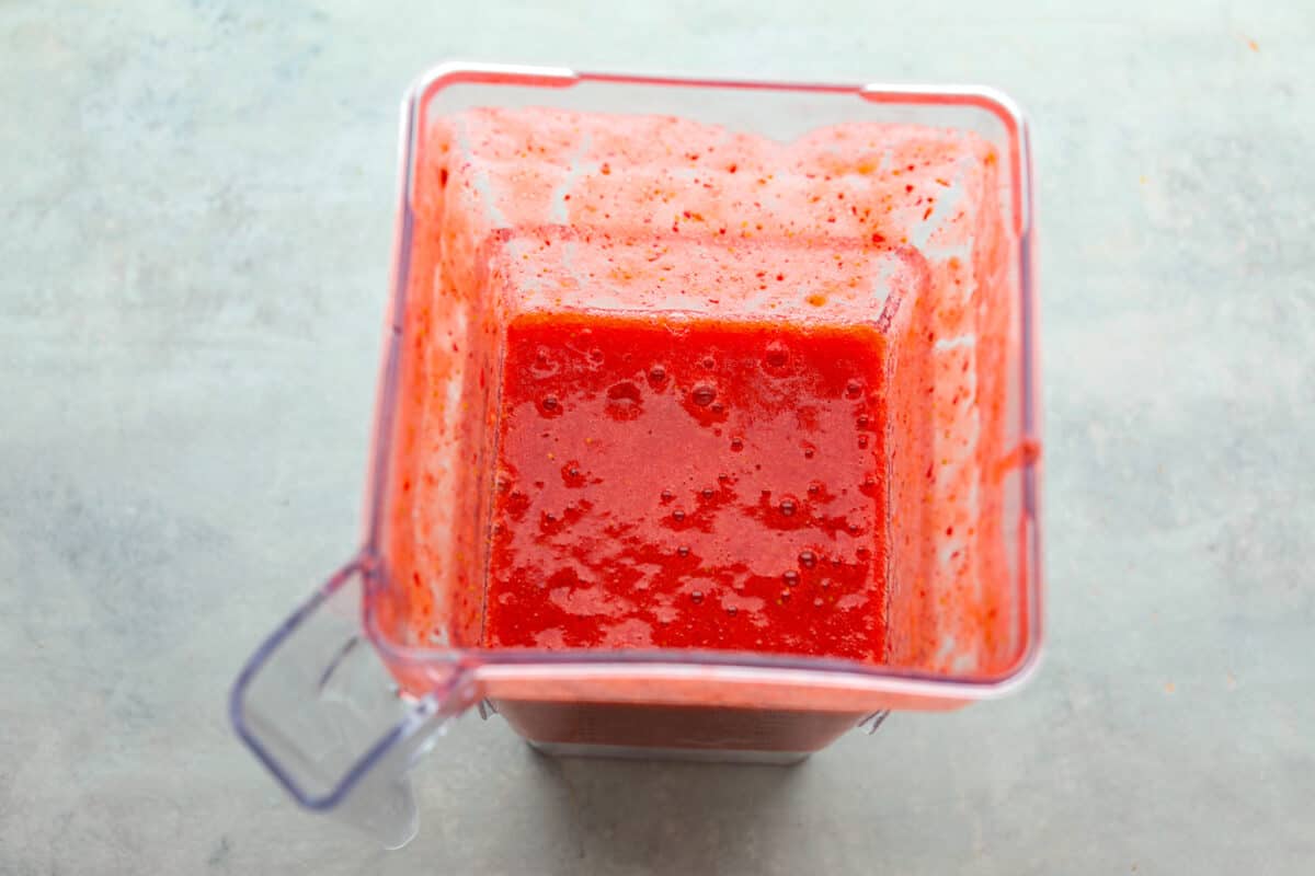 Elevate the flavors of traditional horchata with this strawberry horchata recipe! It's a creamy drink soaked in rice water and cinnamon sticks, then sweetened with a strawberry puree. Everyone loves the strawberry version of this rich, milky Mexican drink! Process photo of the strawberry puree blended in a blender.