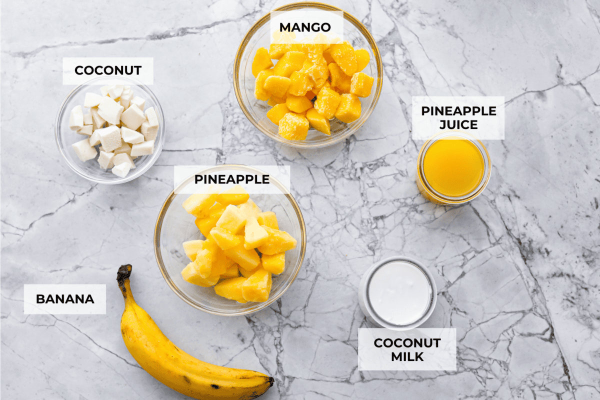 This refreshing tropical smoothie is bursting with tropical fruit flavors, making it the perfect treat for a hot day. Sip it, and you'll feel like you're lounging on the beach, enjoying a drink freshly served by the cabana boy! Overhead shot of labeled smoothie ingredients.