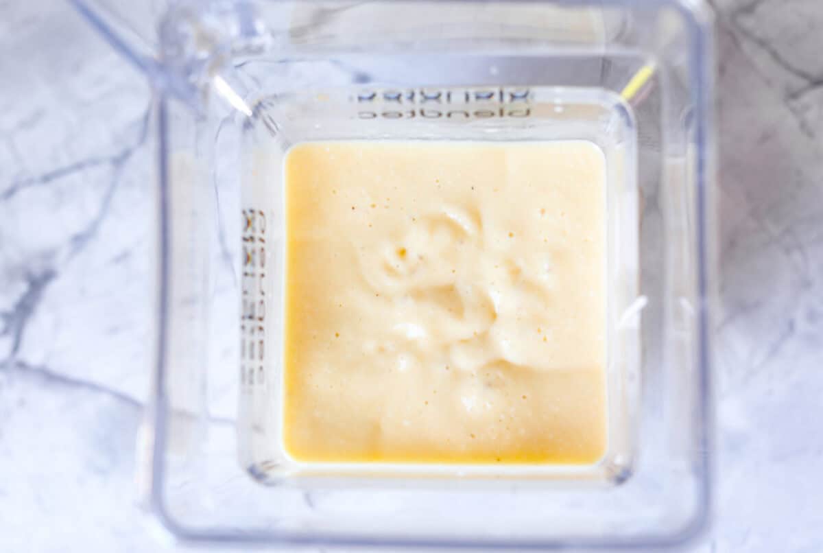 This refreshing tropical smoothie is bursting with tropical fruit flavors, making it the perfect treat for a hot day. Sip it, and you'll feel like you're lounging on the beach, enjoying a drink freshly served by the cabana boy! Overhead shot of blended up tropical smoothie ingredients.