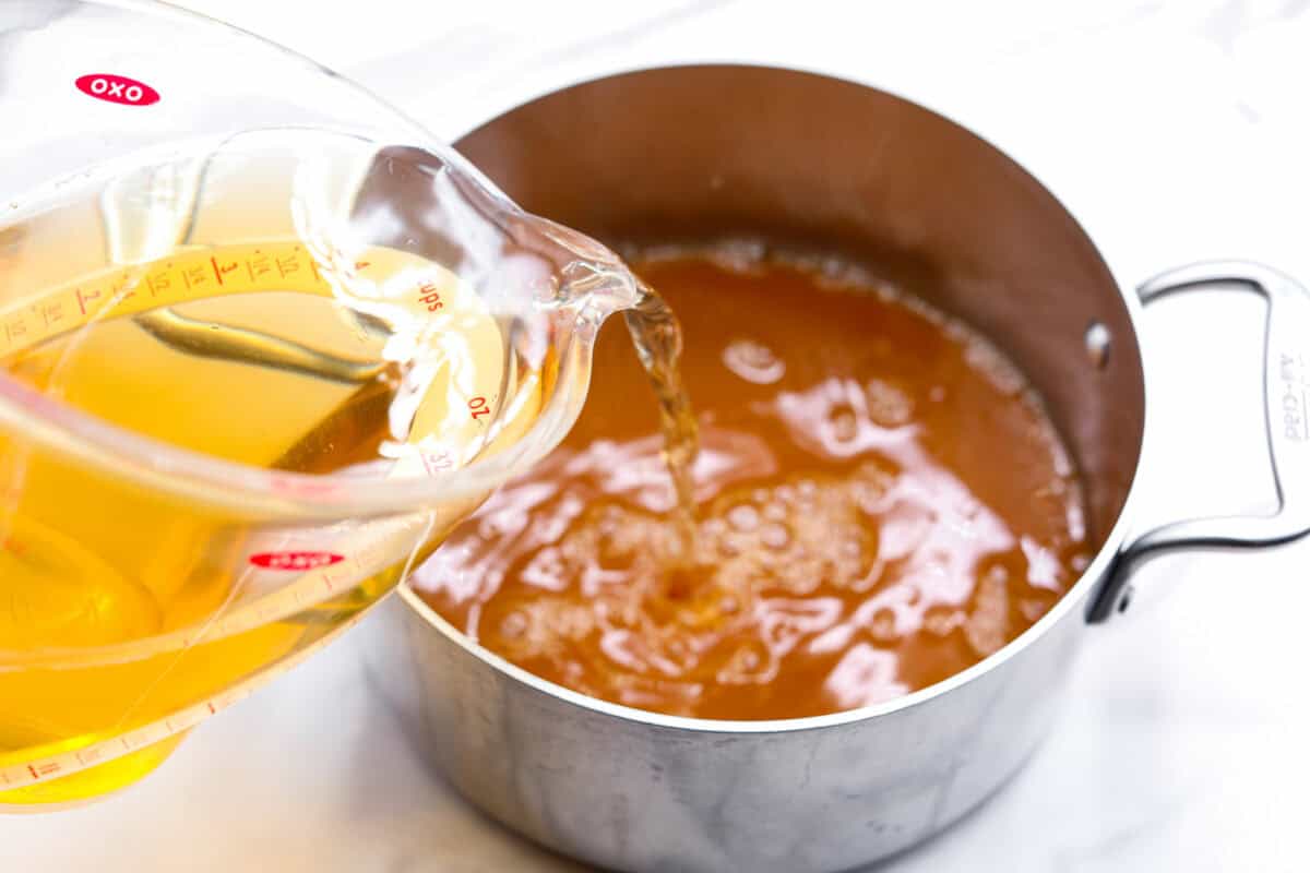 This Harry Potter Pumpkin Juice will transport you to a magical ride on the Hogwarts Express or eating lunch with your friends in the great hall. Bursting with warm, cozy fall flavor, you will love feeling part of the wizarding world of Harry Potter with this magical drink. Overhead shot of someone pouring apple juice into the pan filled with strained juice.