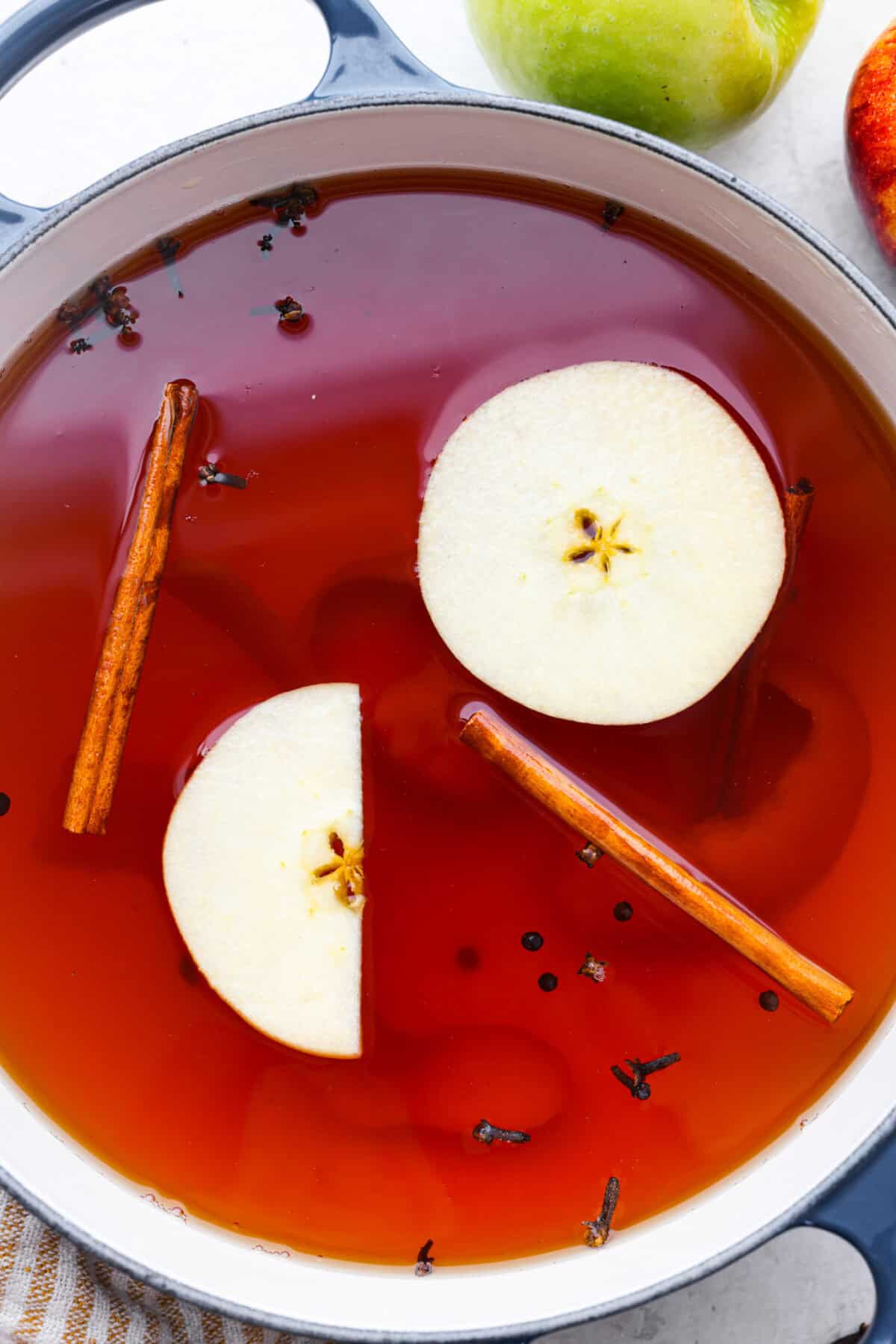 Mulled cider is a warm, inviting drink that is mixed with citrus and spices. Take your apple cider game up a notch with this easy recipe. Your house will smell amazing as well! Overhead shot of mulled cider.