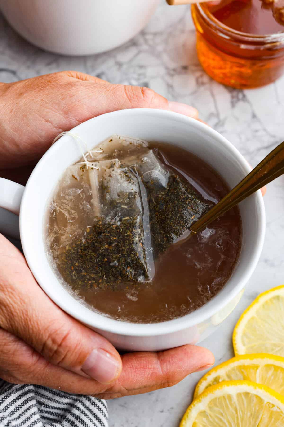 Whenever I am sick, the Starbucks Medicine Ball is my go-to, and this homemade version is even better! Perfect for cold and flu season, this warm drink made of lemonade, honey, and tea is soothing and delicious! Close up shot of a mug of copycat Starbucks medicine ball in a mug.