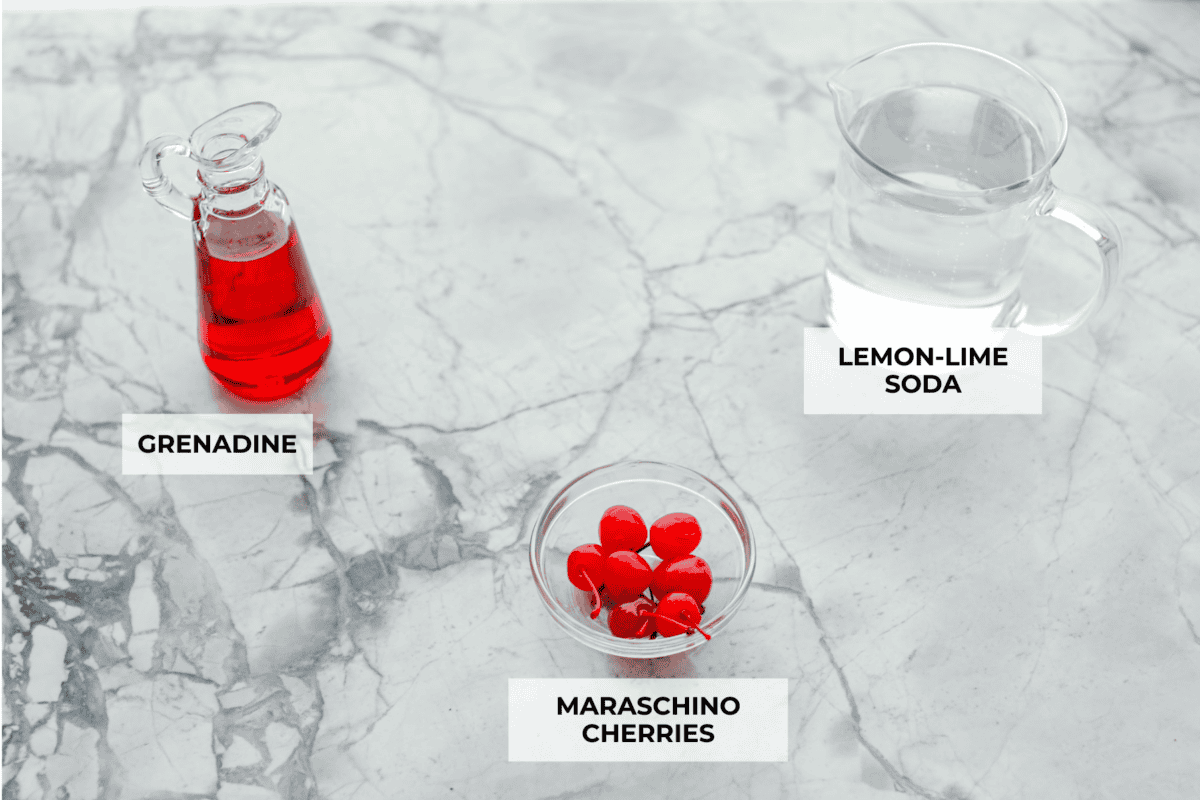 The Shirley Temple is a classic, non-alcoholic drink that's as fun as it is refreshing! Made with just a few simple ingredients, its sweet, bubbly flavor and signature cherry garnish make it a favorite for both kids and adults! Overhead shot of labeled ingredients.